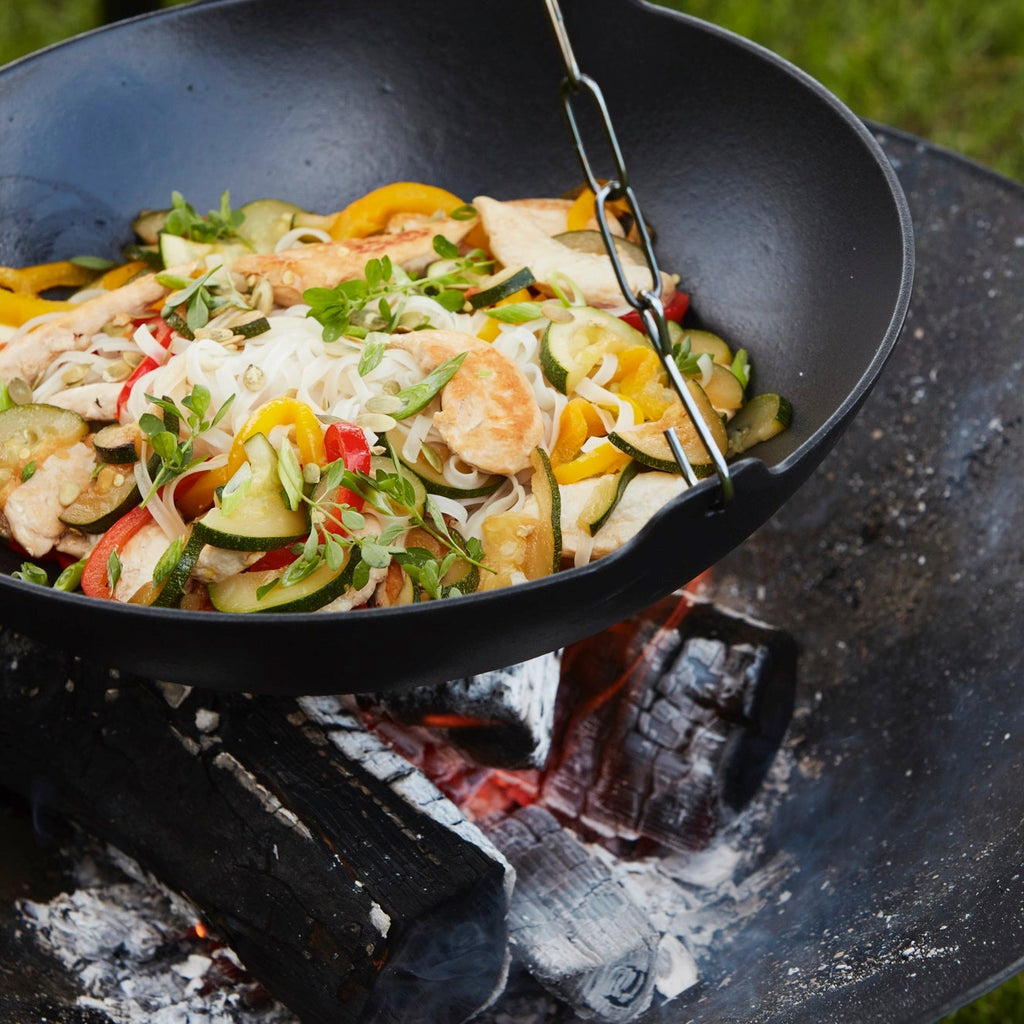 Wok of chicken, noodles and vegetables on the BBQ